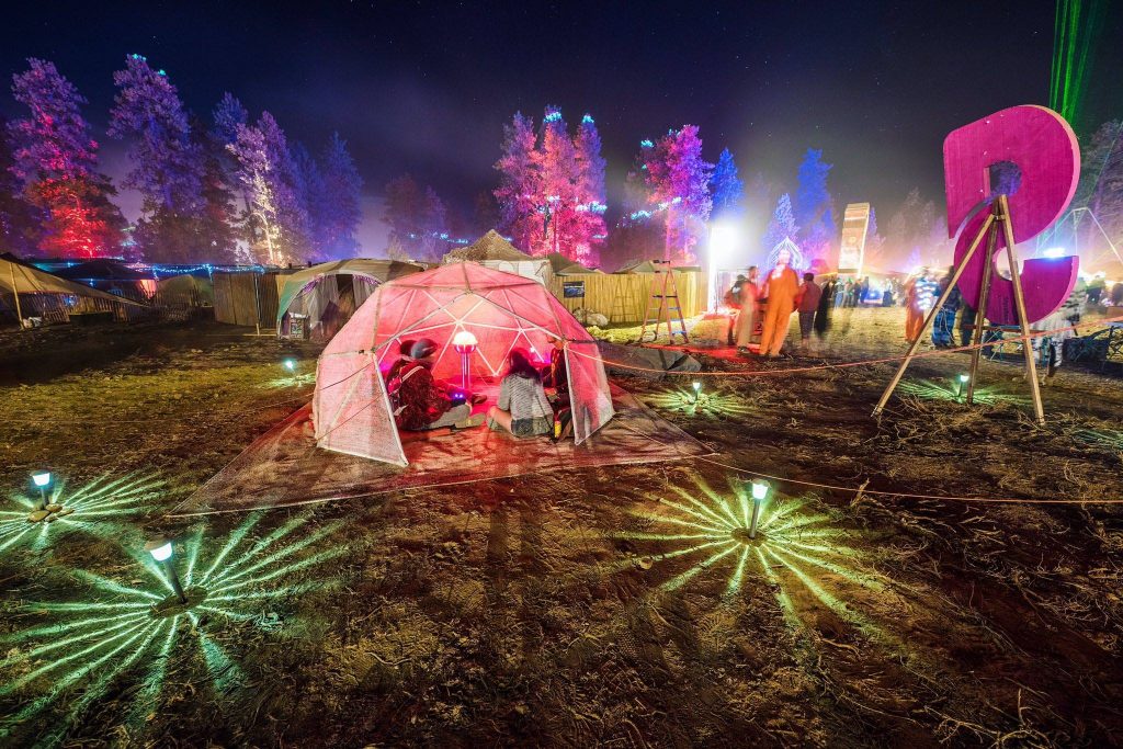 LoveDome: A geodesic dome during the Oregon Eclipse Festival. Inside the dome is a small sculpture and several people.